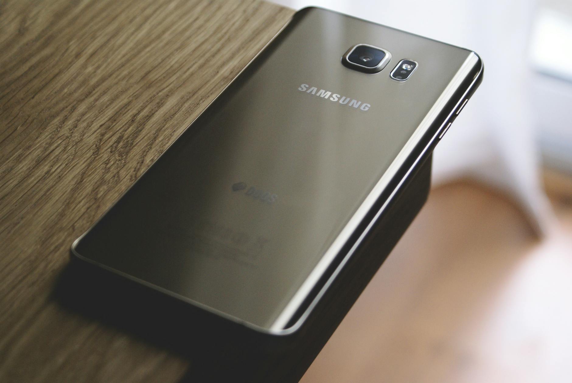 silver samsung galaxy smartphone on top of brown wooden table